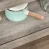 rolling-kitchen-cart-stainless-top_8 Grey woodgrain lower shelf with a raised lip holding a small saucepan